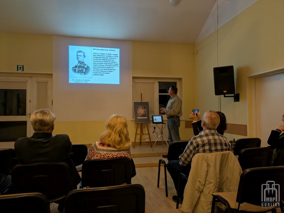 Biblioteka Gorlice, Anton Ludwig Friedrich August von Mackensen sala z gośćmi prelekcji w centralnym punkcie prowadzący pokazuje slajd z życiorysu bohatera spotkania